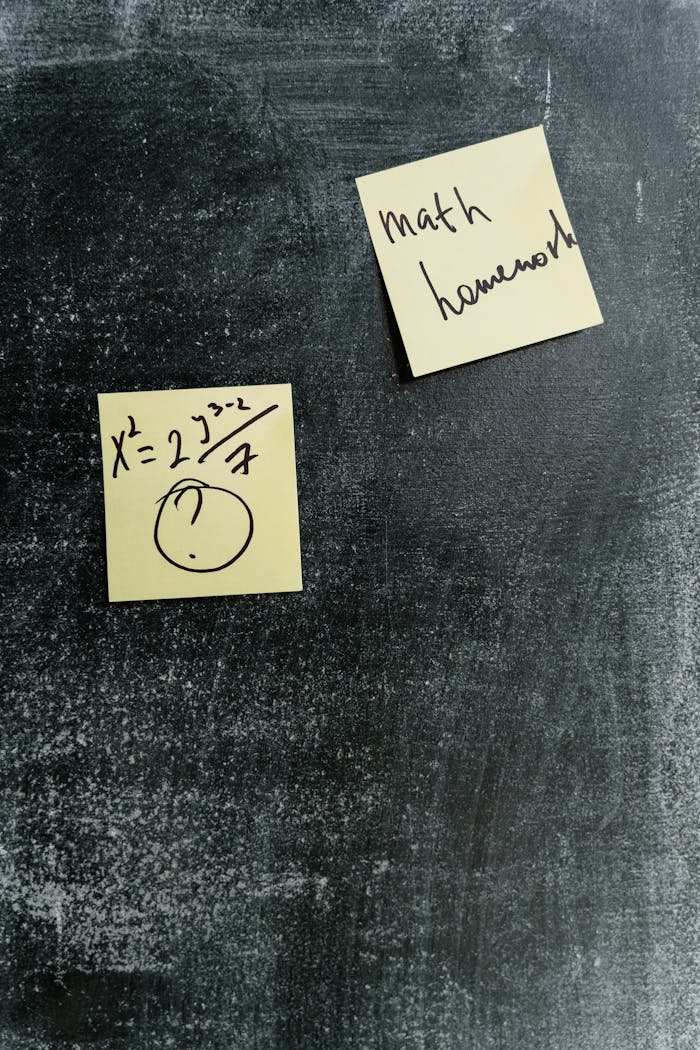 Sticky notes with math equations and homework reminders on a chalkboard.